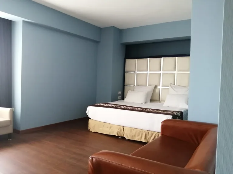 City One Hotel Kayseri şehir süitinde çift kişilik yatak ve ceviz tonlu oturma grubu